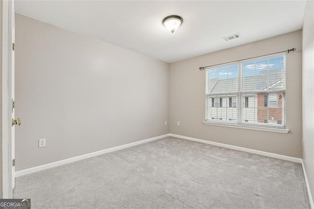 spare room featuring visible vents, baseboards, and light colored carpet