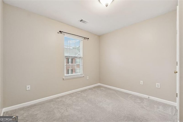 empty room featuring light colored carpet, visible vents, and baseboards