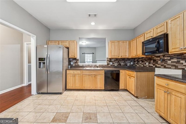 kitchen featuring black appliances, light tile patterned floors, visible vents, and a sink