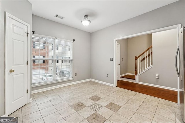 unfurnished room with light tile patterned floors, baseboards, stairs, and visible vents