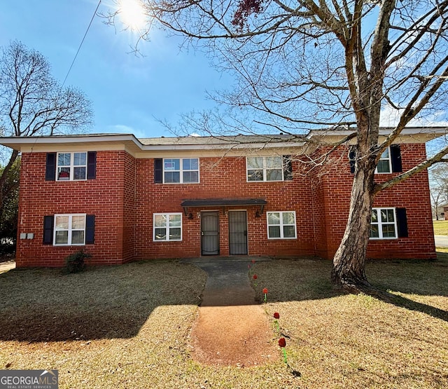 view of front of house featuring a front yard, a patio, and brick siding