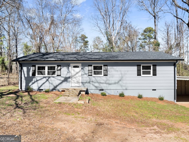 ranch-style home with entry steps, a shingled roof, crawl space, a front lawn, and a carport