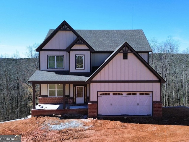 view of front of property with an attached garage, a shingled roof, a porch, and brick siding