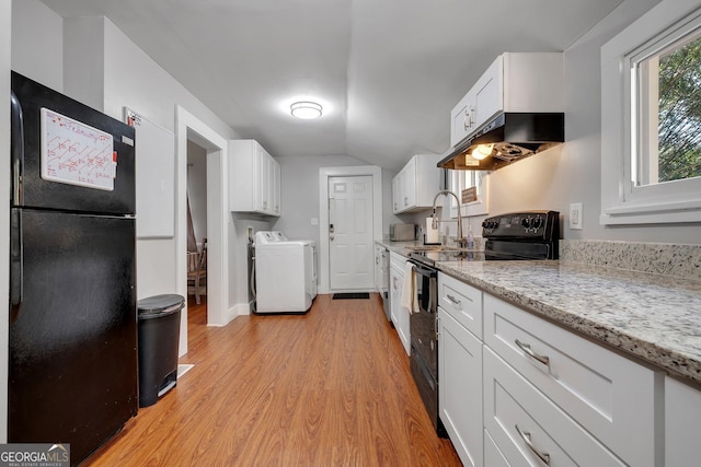 kitchen featuring light stone counters, under cabinet range hood, washer and dryer, white cabinets, and black appliances