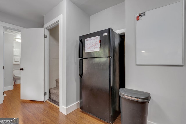 kitchen featuring baseboards, wood finished floors, and freestanding refrigerator