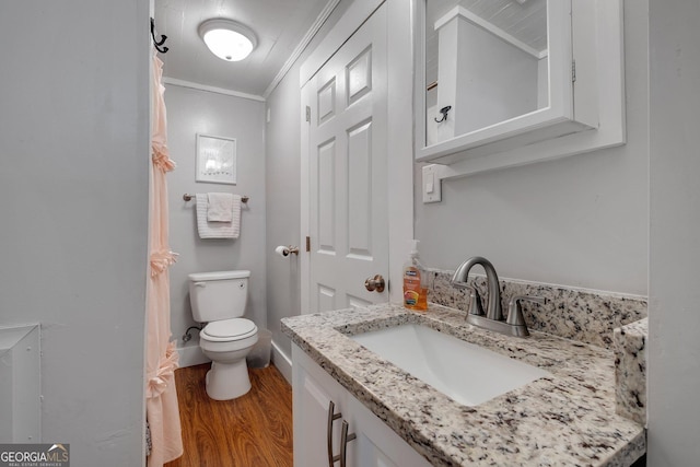 bathroom featuring toilet, wood finished floors, vanity, baseboards, and ornamental molding