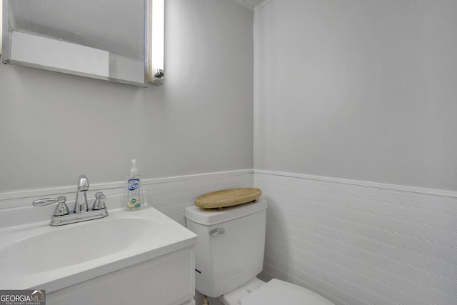 bathroom featuring toilet, vanity, and wainscoting