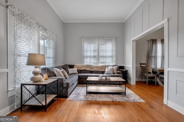 living room featuring light wood-style floors, a wealth of natural light, and crown molding