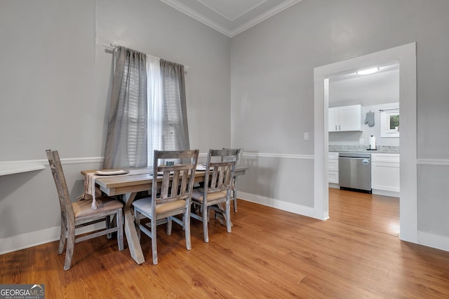 dining area with light wood-style flooring, ornamental molding, and baseboards