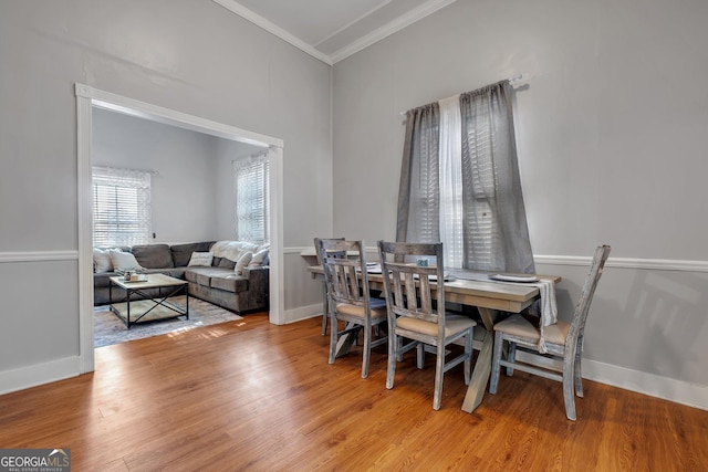 dining area with ornamental molding, light wood-style flooring, and baseboards