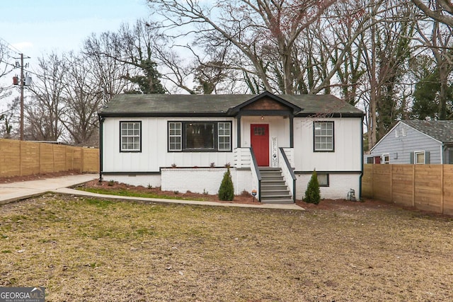 view of front facade featuring fence private yard, a front lawn, and board and batten siding