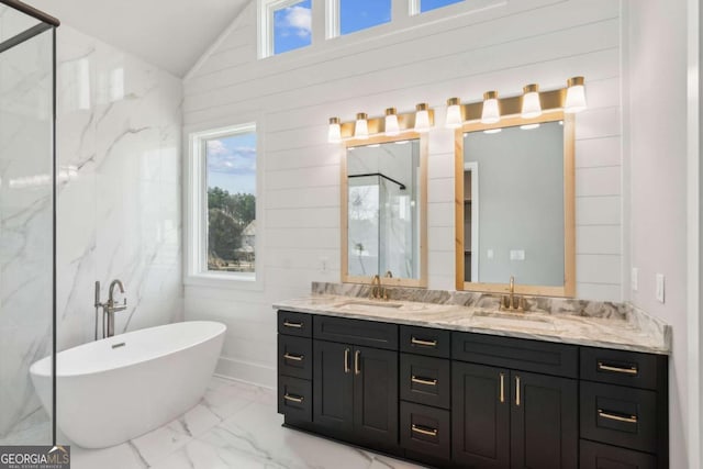 bathroom with marble finish floor, double vanity, lofted ceiling, a soaking tub, and a sink