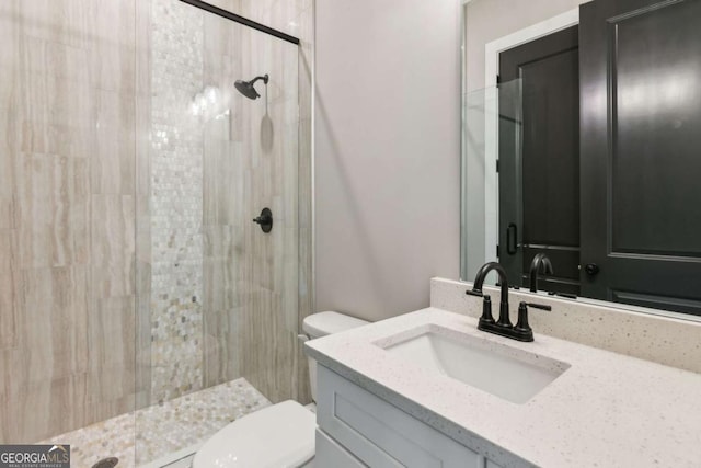 full bathroom with a tile shower, vanity, and toilet