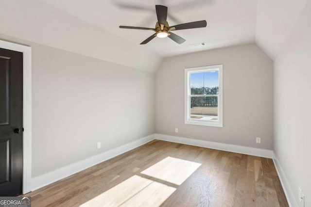 additional living space featuring light wood-type flooring, visible vents, vaulted ceiling, and baseboards