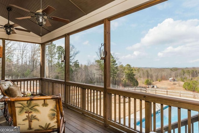 deck featuring a fenced backyard, a wooded view, an outdoor pool, and a ceiling fan