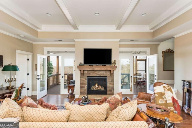 living area with crown molding, dark wood finished floors, beam ceiling, and a stone fireplace