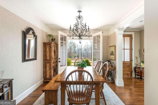 dining room featuring an inviting chandelier, decorative columns, baseboards, and dark wood finished floors