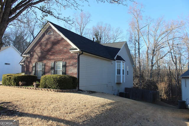 view of side of property with brick siding, a lawn, and cooling unit