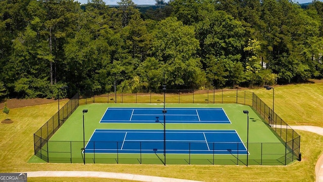 view of tennis court featuring a yard and fence