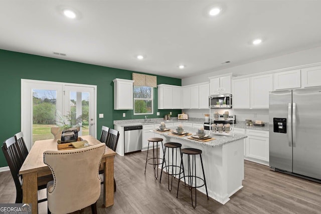 kitchen featuring light wood-style floors, white cabinetry, a kitchen island, and appliances with stainless steel finishes