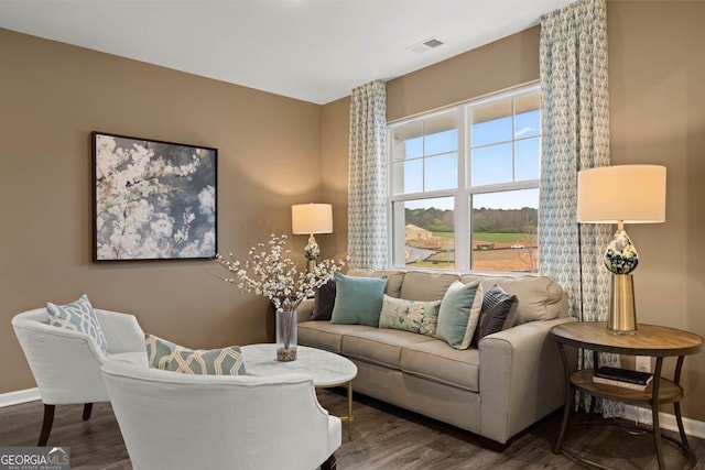 living room featuring visible vents, baseboards, and wood finished floors