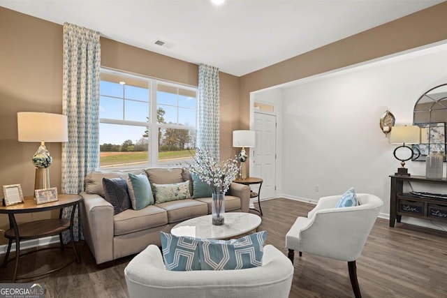 living area featuring dark wood-style flooring, visible vents, and baseboards