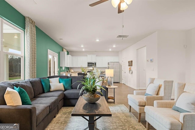 living area with ceiling fan, light wood-style flooring, recessed lighting, visible vents, and baseboards