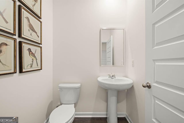 bathroom with toilet, baseboards, and wood finished floors