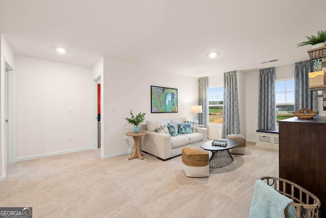 living area featuring light colored carpet, a healthy amount of sunlight, and visible vents