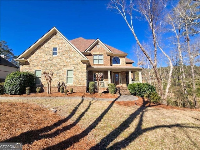 view of front of house featuring a porch, brick siding, and a front lawn