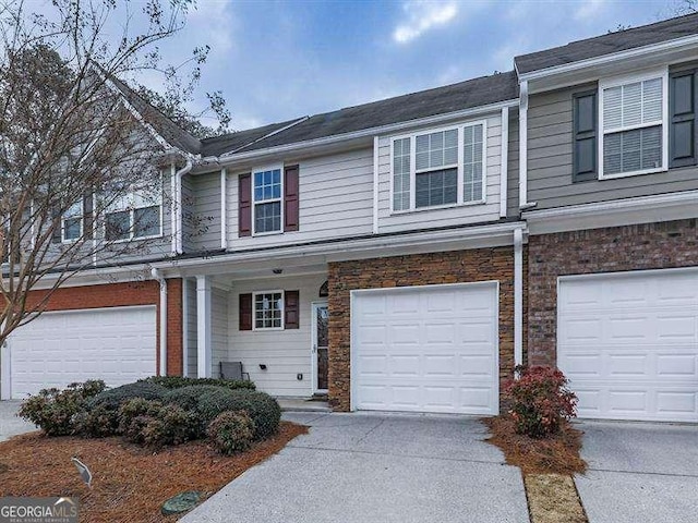 view of property featuring a garage, brick siding, and driveway