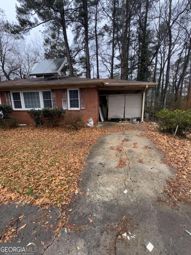 view of front of house featuring driveway, roof mounted solar panels, a carport, and brick siding