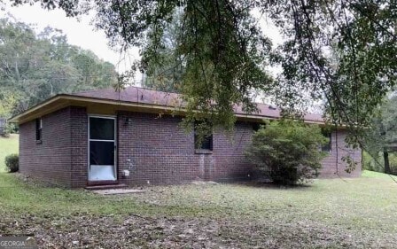 back of property with brick siding and a yard