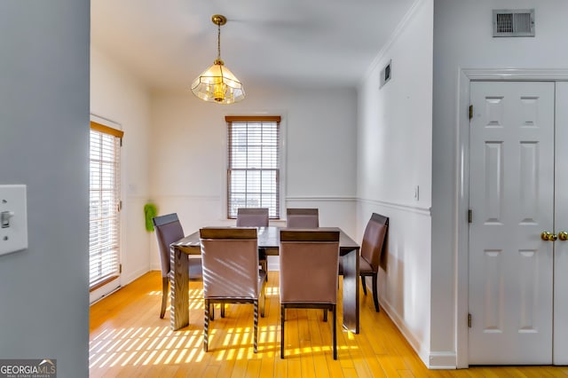 dining room featuring light wood finished floors, baseboards, and visible vents