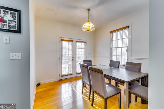 dining room featuring french doors, baseboards, plenty of natural light, and light wood finished floors