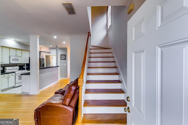 staircase with baseboards, visible vents, ornamental molding, wood finished floors, and recessed lighting