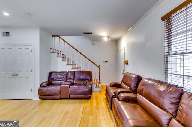 living room with stairs, visible vents, crown molding, and wood finished floors