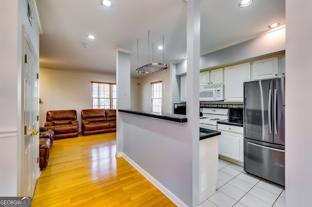 kitchen featuring open floor plan, white appliances, dark countertops, and white cabinetry