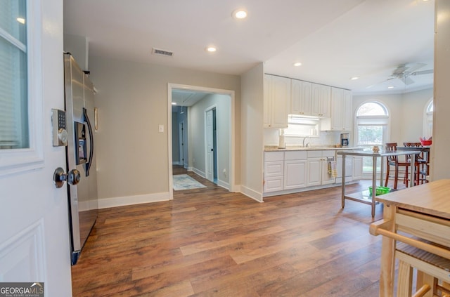 kitchen featuring wood finished floors, visible vents, white cabinets, light countertops, and stainless steel refrigerator with ice dispenser