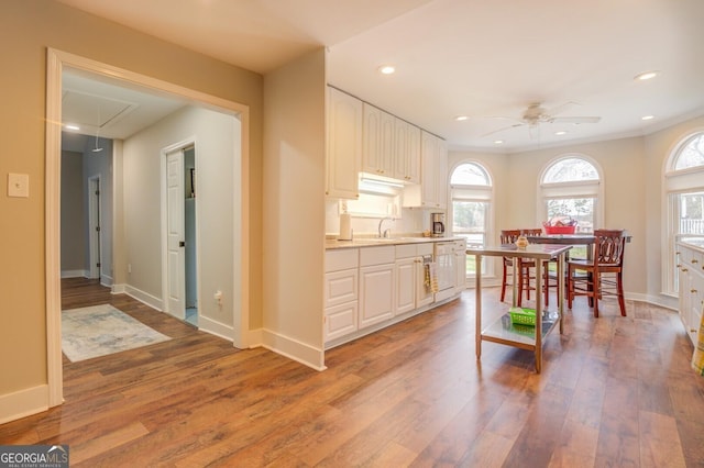 kitchen featuring baseboards, light countertops, light wood finished floors, and white cabinets