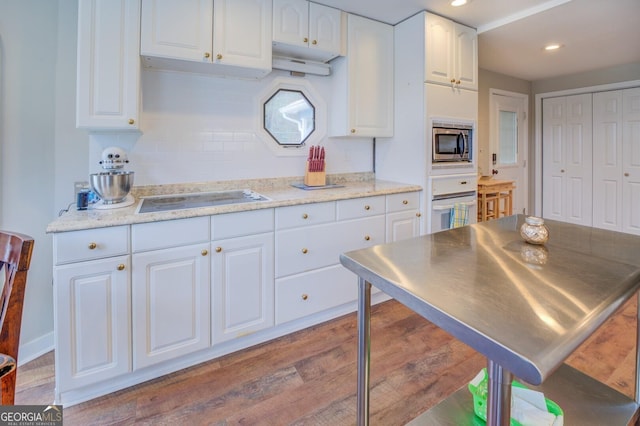 kitchen featuring white cabinetry, white oven, tasteful backsplash, stainless steel microwave, and cooktop