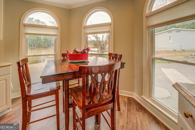 dining space featuring baseboards, wood finished floors, and crown molding