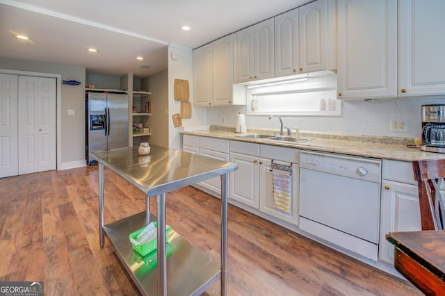 kitchen featuring stainless steel refrigerator with ice dispenser, light wood-style floors, white cabinetry, white dishwasher, and a sink