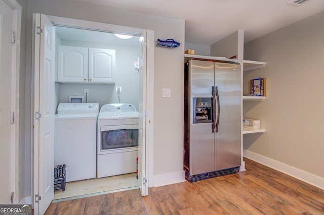 laundry room with cabinet space, independent washer and dryer, baseboards, and wood finished floors