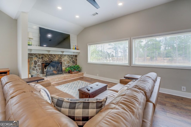 living room with a stone fireplace, wood finished floors, visible vents, and baseboards