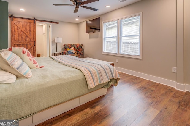 bedroom featuring recessed lighting, dark wood finished floors, baseboards, and a barn door