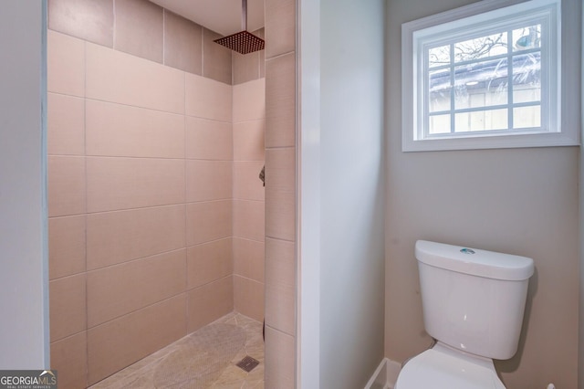 bathroom featuring tiled shower and toilet