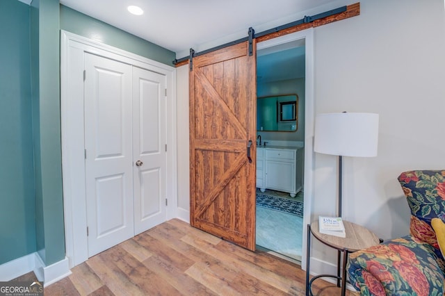 bedroom featuring light wood-style floors, recessed lighting, baseboards, and a barn door