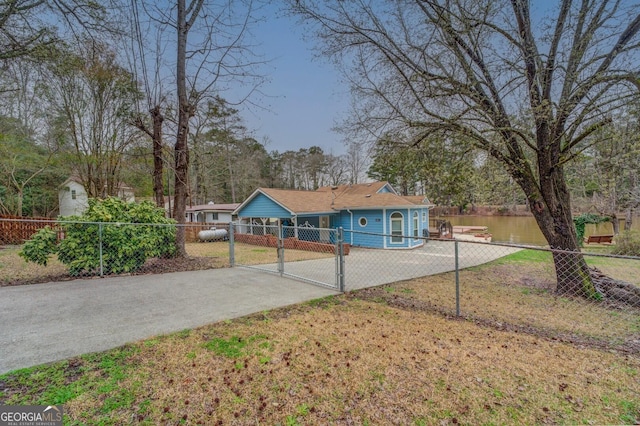 single story home featuring a gate, a water view, driveway, and fence