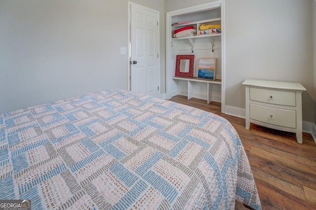 bedroom with a closet, dark wood finished floors, and baseboards